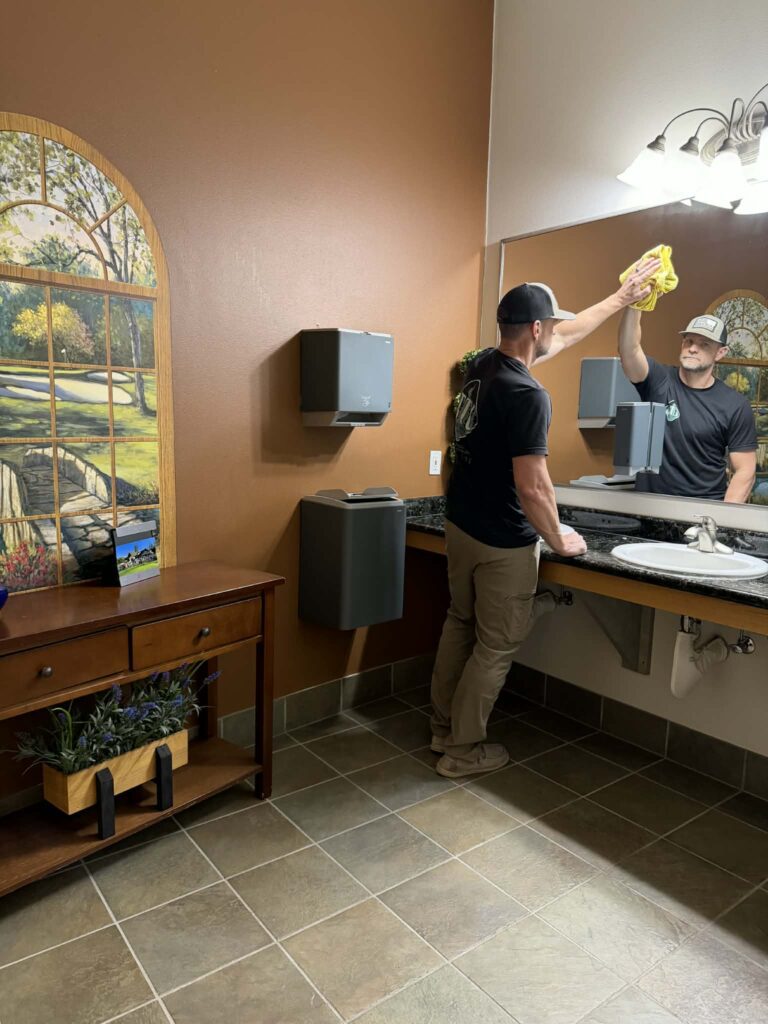 Owner cleaning a bathroom window in Grants Pass, Oregon | Three Trees Cleaning